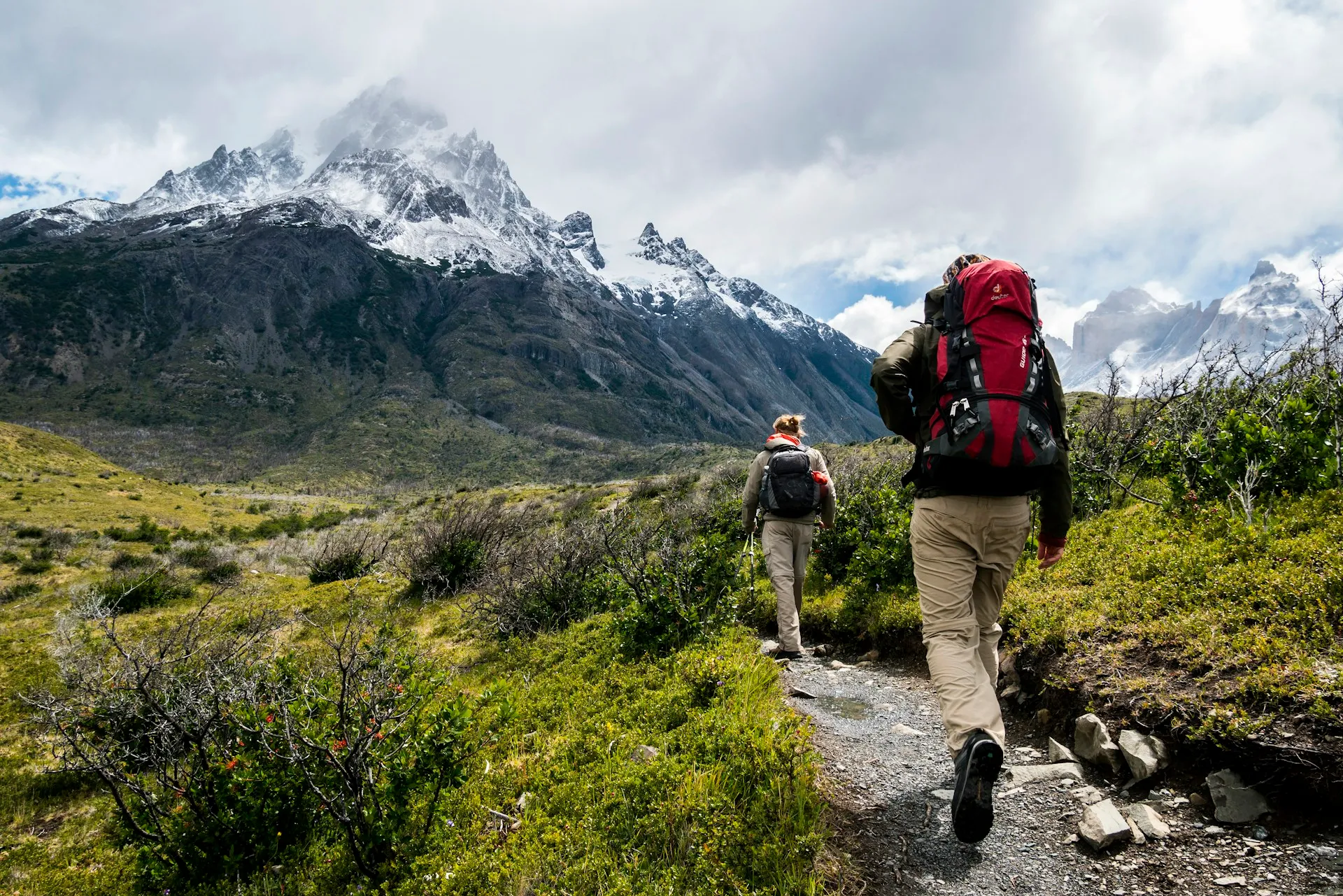 Exploradores com mochilas subindo uma trilha de montanha